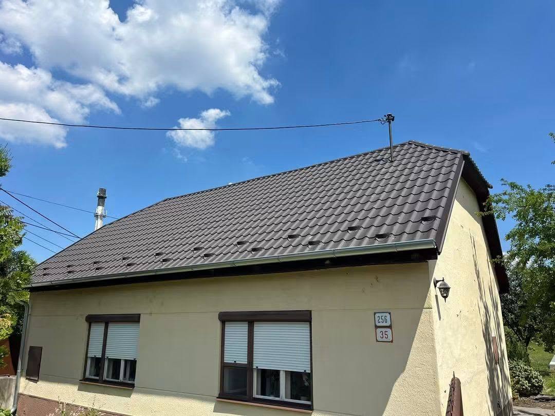 Elkészült tető: Régi palatető helyett sötétbarna cserepeslemez, új bádogozással és ereszcsatornával.